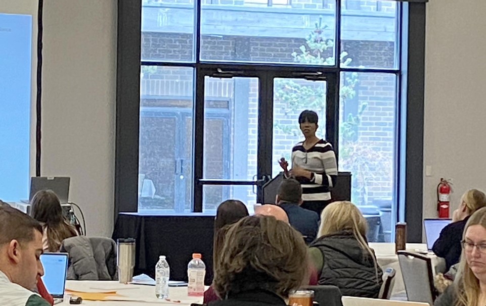 afican american lady presenting and people sitting at tables