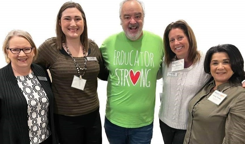 4 ladies standing with a guy in the middle all smiling
